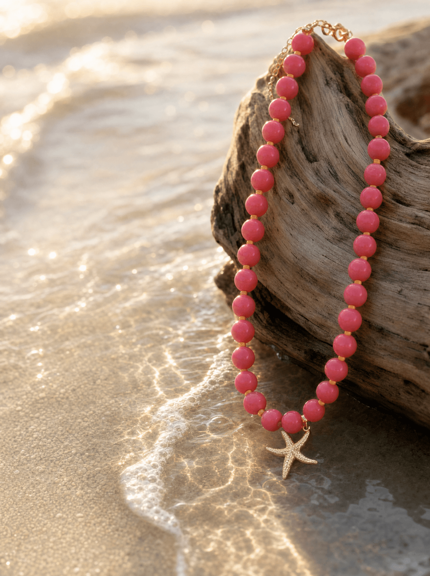Collar de ágata rosada con estrella de mar sobre madera de deriva a la orilla del mar.