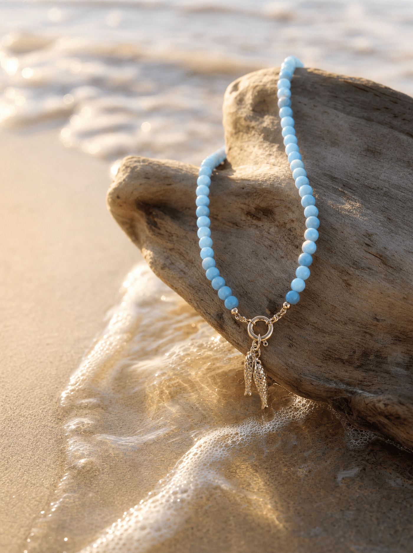 Collar de jade azul sobre madera de deriva a la orilla del mar al atardecer.