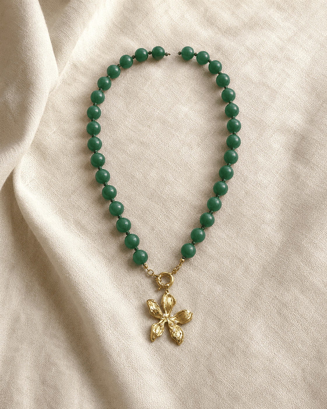 Collar Marea Verde completo extendido en arco sobre lino marfil, mostrando todas las cuentas y el dije.