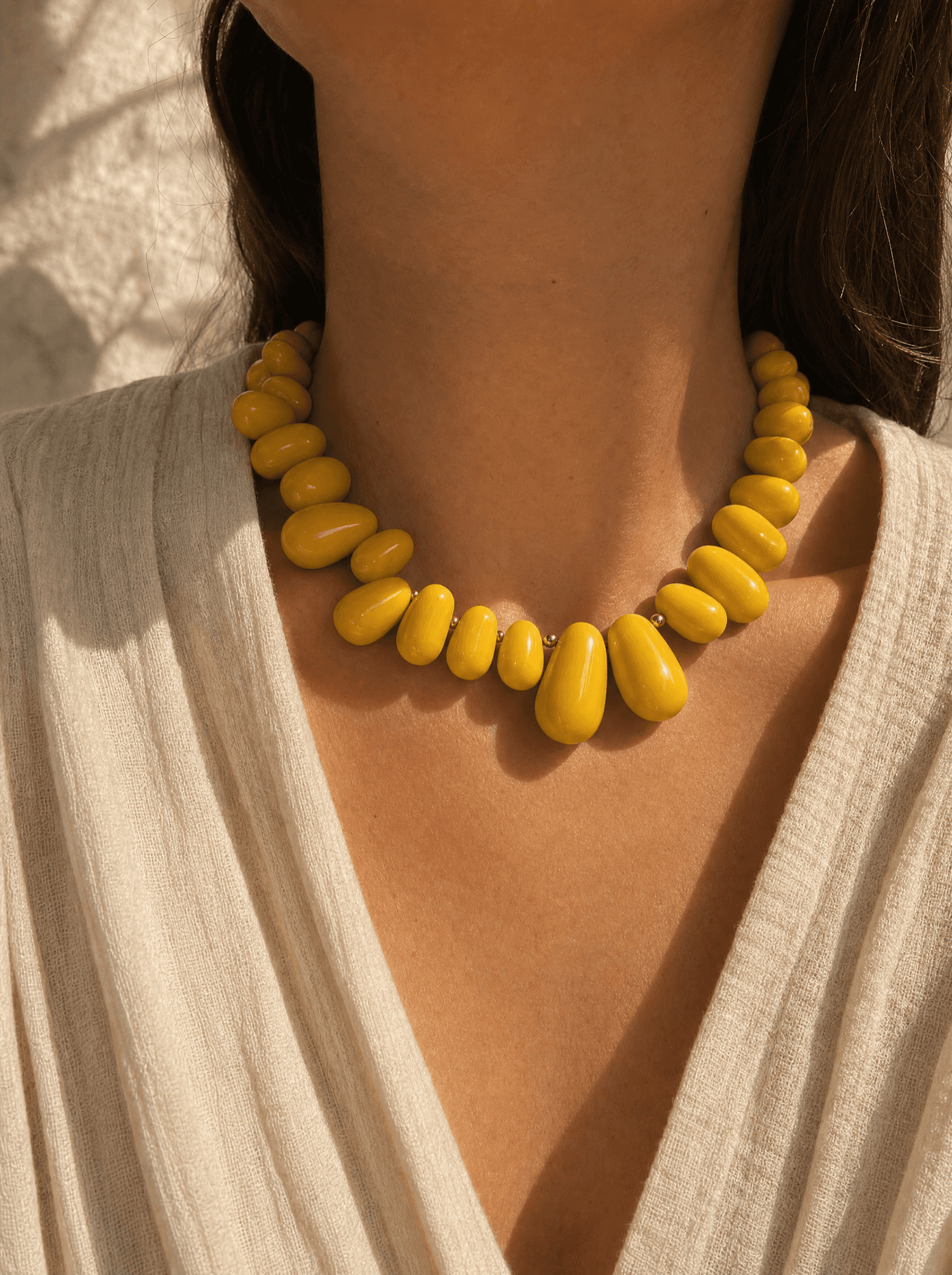 Collar statement de grandes gotas amarillas pulidas con acentos dorados sobre cuello de mujer.